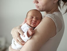 Gentle mother holds in her arms a sleeping newborn baby